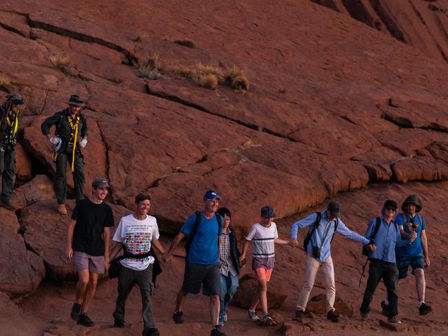 The final climbers held hands and stepped off Uluru together at 7.12pm on the last day the climb was open. Friday 25 October 2019. Photo: EMMA MURRAY