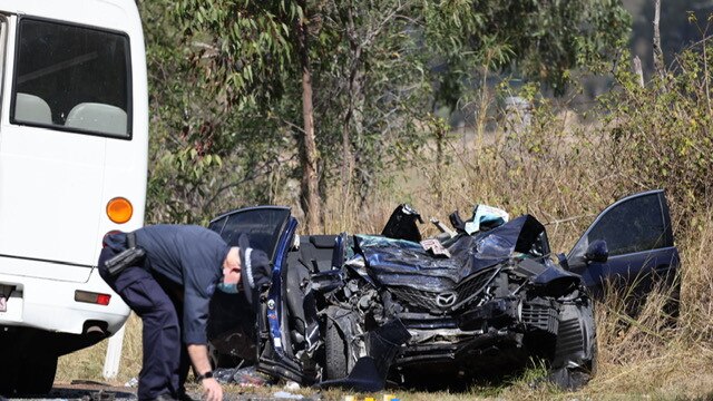 A police officer inspects the scene following a crash near Tamborine. Picture: Peter Wallis