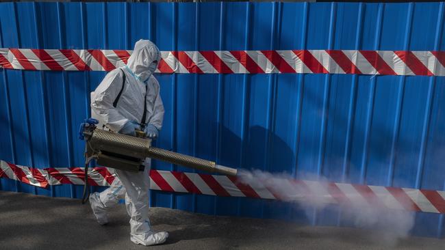 A health worker wears a protective suit as he disinfects an area outside a barricaded community in Beijing that was locked down for health monitoring after recent cases of Covid. Picture: Kevin Frayer/Getty Images