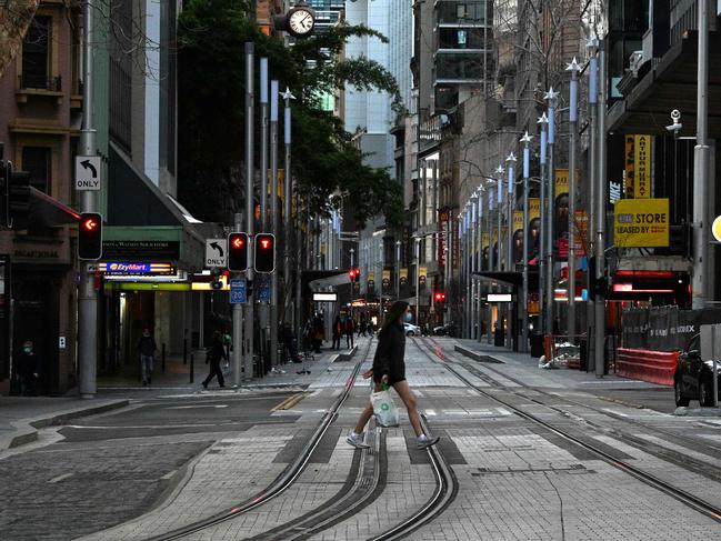 This picture taken on August 27, 2021 shows a girl wearing a face mask walking through the empty streets of the central business district in Sydney during the lockdown. (Photo by Saeed KHAN / AFP)