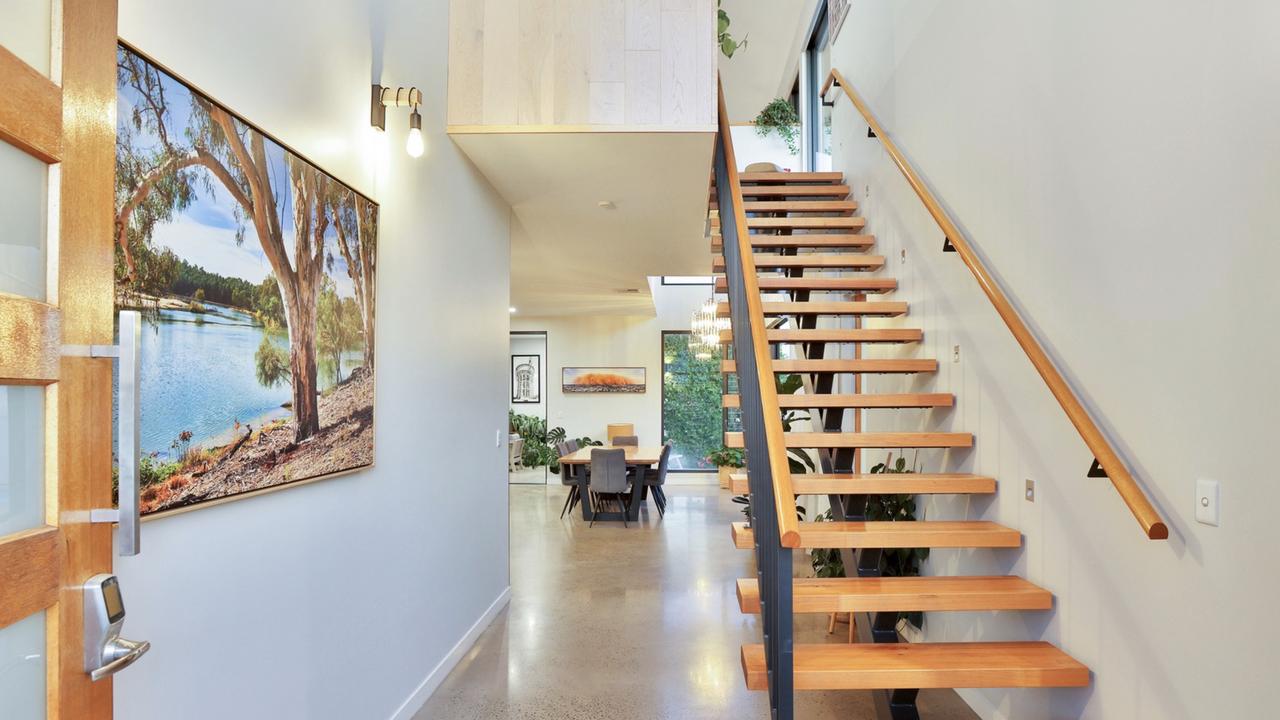 View looking from the hallway into the open living area and the stairs to the right.