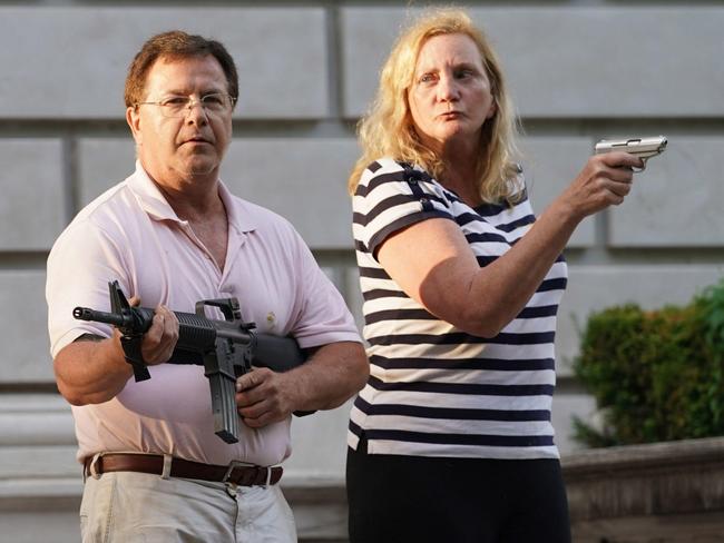 ONE TIME WEB USE ONLY - FEES APPLY FOR REUSE - MUST REDOWNLOAD FROM ALAMY - 2C4TM5Y St. Louis, United States. 28th June, 2020. A husband and wife hold a pistol and automatic rifle as protesters walk past their house en route to St. Louis Mayor Lyda Krewson's home during a protest march in St. Louis on Sunday, June 28, 2020. The man and woman greeted about 300 protesters, shouting as they broke down a gate in the neighborhood to march past their home. No shots were fired and the protesters moved on. Picture: Bill Greenblatt/UPI/Alamy Live News