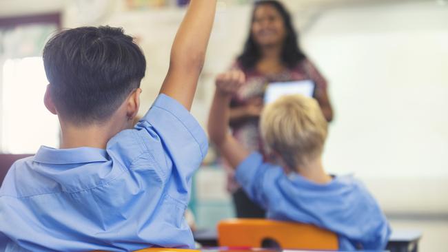 Aboriginal Elementary school  teacher giving a presentation to the class. The students have their hands raised to ask  questions in the classroom  Picture: istock