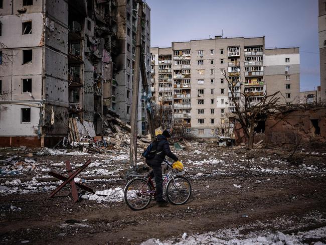 A man rides his bicycle in front of residential buildings damaged in the shelling in the city of Chernihiv on March 4, 2022. Picture: Dimitar DILKOFF / AFP