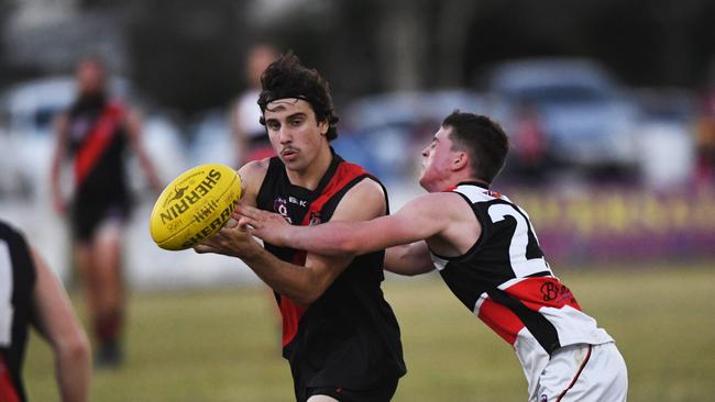 Wide Bay AFL - Hervey Bay Bombers (black) v Brothers Bulldogs (white) - Todd Baldwin gets the ball away under pressure.