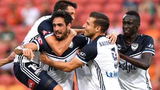 Victory defender Rhys Williams is mobbed by teammates after scoring the opening goal against Brisbane Roar at Suncorp Stadium last night. Picture: Getty Images