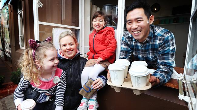 Co-owner of Cafe Bliss in East Brighton Kel Dondup hanging out the takeaway coffee window with Gabby 4, Ellie 4 and mum Jenny Shakespeare. Picture: Rebecca Michael