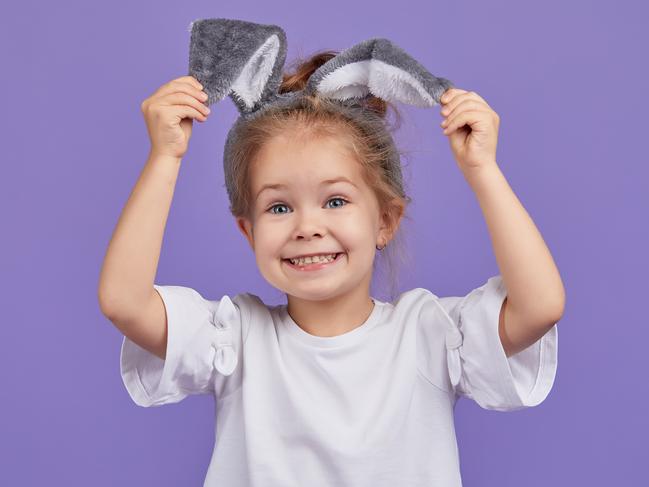 Portrait of cute smiling little child girl wears bunny ears on Easter day. Funny emotions on Violet isolated background