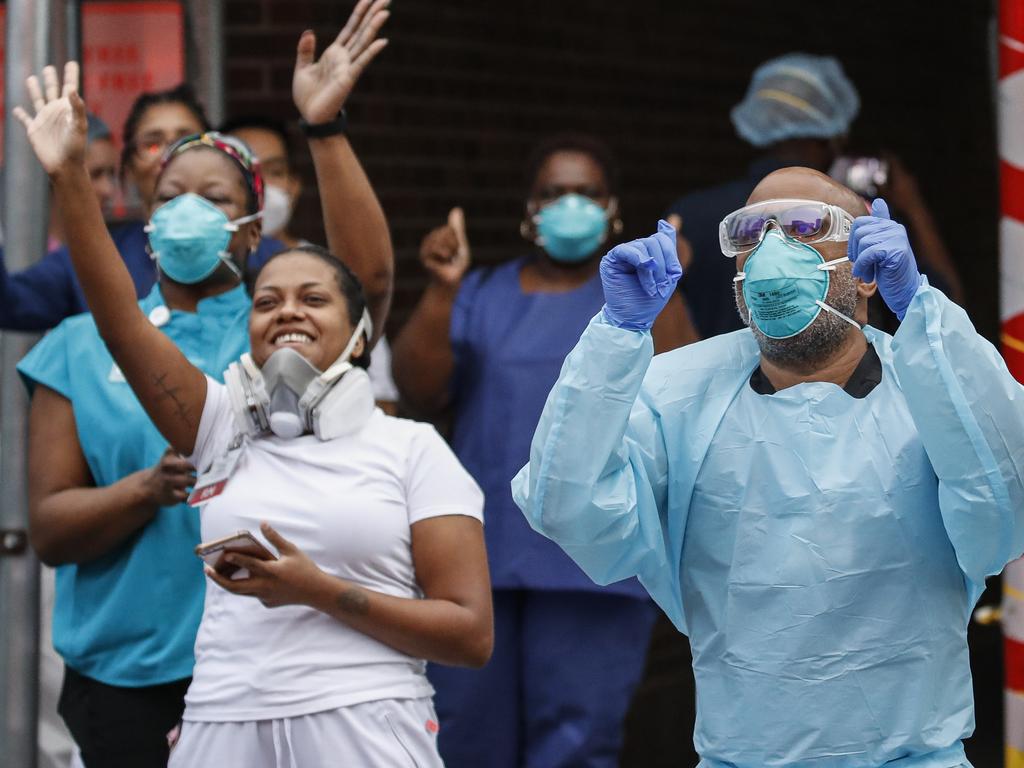 Medical workers cheer and acknowledge pedestrians and FDNY firefighters who gathered to applaud them at 7pm outside Brooklyn Hospital Center in New York. Picture: AP