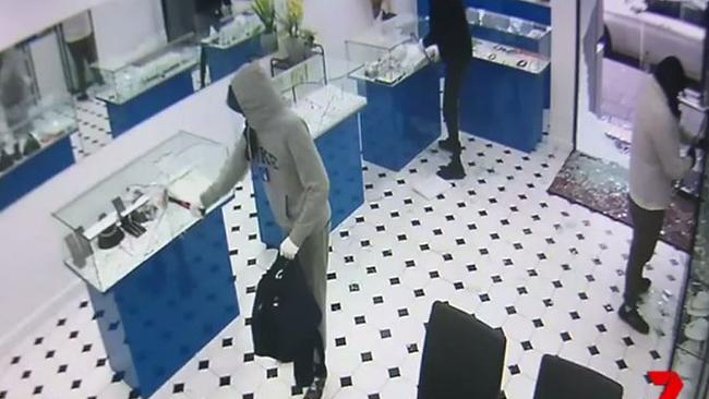 One of the thieves smashes a glass case with his hammer.