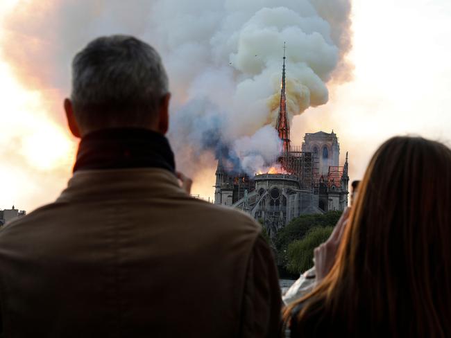 People react as they watch flames engulf the roof of the Notre-Dame de Paris Cathedral in the French capital Paris on April 15, 2019. (Photo by GEOFFROY VAN DER HASSELT / AFP)