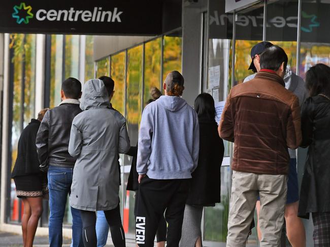 People queue up outside a Centrelink office in Melbourne on April 20, 2020, which delivers a range of government payments and services for retirees, the unemployed, families, carers and parents amongst others. - A report from the Grattan Institute predicts between 14 and 26 per cent of Australian workers could be out of work as a direct result of the coronavirus shutdown, and the crisis will have an enduring impact on jobs and the economy for years to come. (Photo by William WEST / AFP)