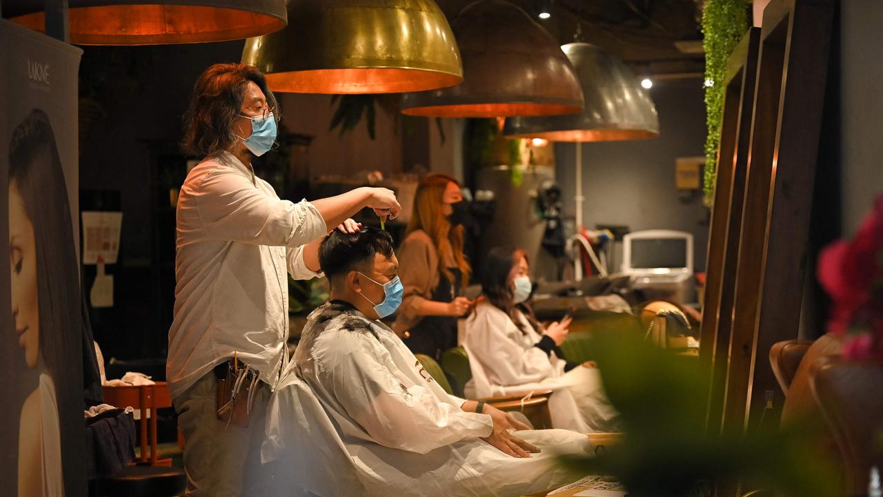 People have their cut at a salon. Picture: Steven Saphore / AFP