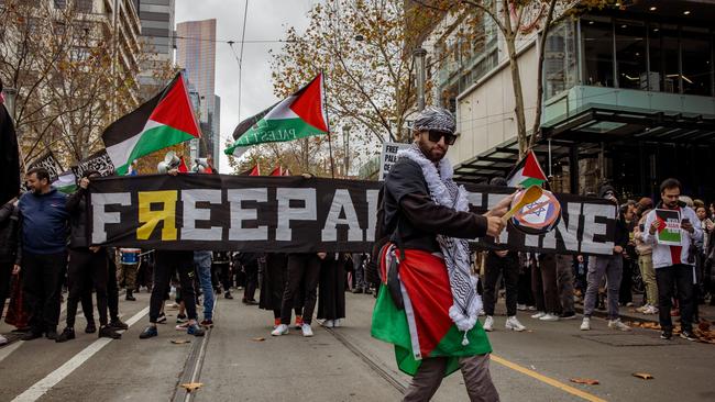 Pro-Palestine supporter plays the drum with a sticker of Israel crossed out in Melbourne. Picture: NewsWire / Tamati Smith