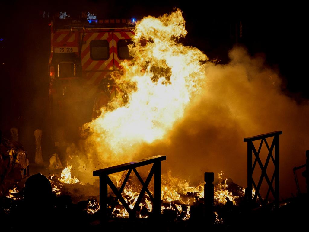 A firefighter extinguishes the flames of a car set on fire during protests in Nanterre, west of Paris (Photo by Geoffroy VAN DER HASSELT / AFP)