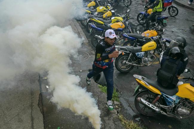 A demonstrator runs away from teargas during a protest against Venezuelan President Nicolas Maduro after he claimed victory in Sunday's election