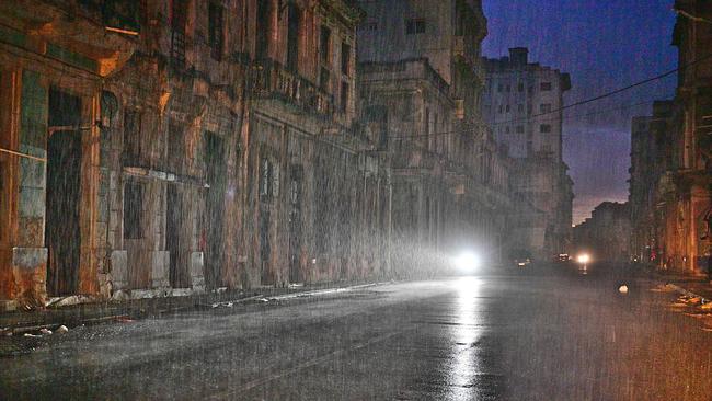 A motorcycle lights a Havana street under pouring rain during a nationwide blackout caused by a grid failure. Picture: AFP