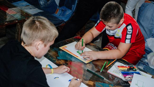 Young refugees from the Kherson region get the textas out at a support centre in Zaporizhzhia this week. Picture: AFP