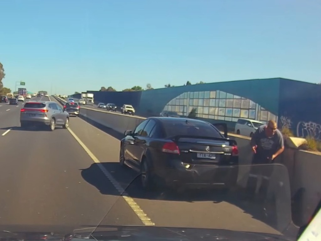 The driver of the car stopped and appeared to yell at the motorcyclist, who was hunched up on the side of the freeway.