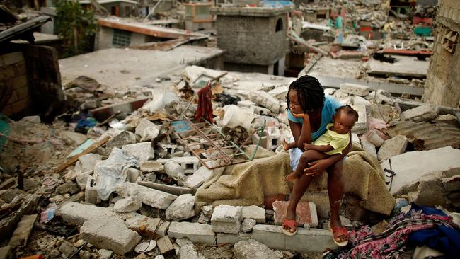 Sherider Anilus and her daughter Monica sit on the spot where their home collapsed during the Haiti earthquake in 2010. Picture: Getty Images