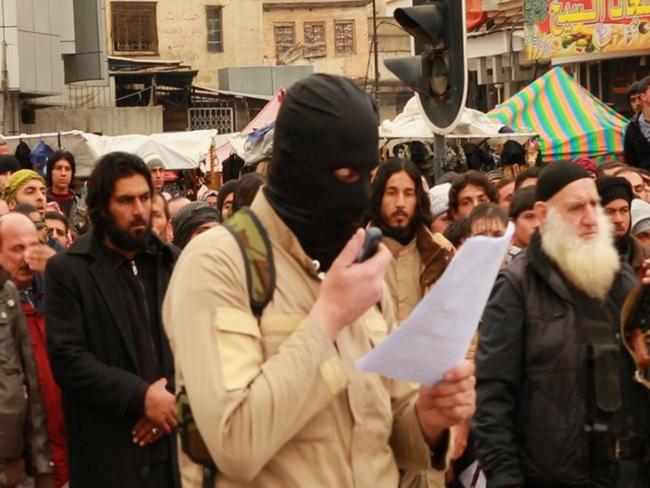 A militant reads out the charges during a public execution in Iraq.