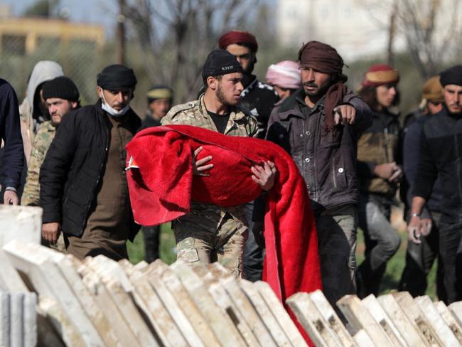 A Syrian fighter carries the body of a child killed in an earthquake in the town of Jandaris, in Syria's rebel-held part of Aleppo province. Picture: AFP