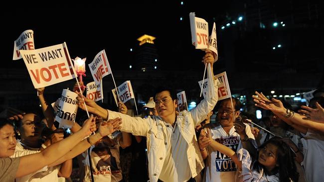 A Thai pro-election activist distributes flags carrying slogans during protests in Bangkok. Picture: AFP