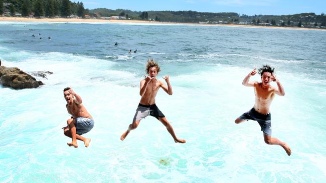 Austin McAlpine, Rory Mackintosh and Ryan Birch, cool off at Avoca Beach Point, Sydney, as temperatures reach 37c on the Central Coast. Picture: Peter Clark