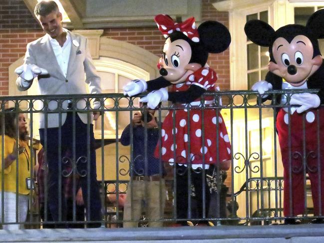 BYE FOR NOW: With Minnie and Mickey Mouse, Walt Disney World President Josh D'Amaro waves to guests gathered on Main Street USA, in the Magic Kingdom in the final minutes before the park closed on Sunday night in Lake Buena Vista, Florida. Picture: Joe Burbank/Orlando Sentinel)/Orlando Sentinel via AP