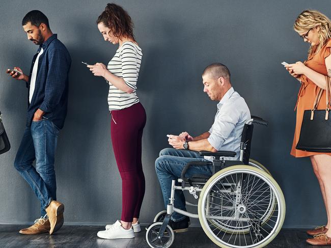 CAREERS: Studio shot of a man in a wheelchair waiting in line against a grey background