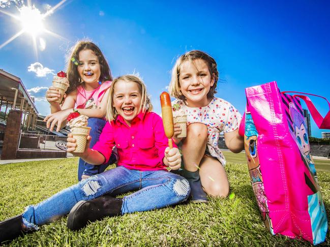 Ella Carew, Emily and Louise Hardy with the Ekka’s trademark strawberry sundaes and dagwood dog. Picture: Nigel Hallett