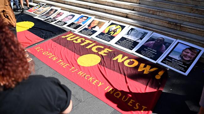 An indigenous flag in front of signs of First Nations people who have died in custody is seen during a Black Death in Custody Rally at Town Hall in Sydney in early 2021, 30 years since the royal commission into Aboriginal deaths in custody handed down its final report. At least 474 Aboriginal and Torres Strait Islander peoples have died in custody since then. Picture: Bianca De Marchi