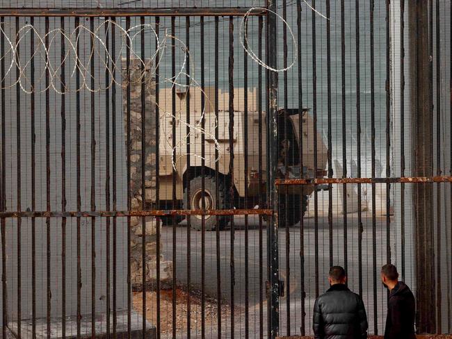 Displaced Palestinian men watch as an Egyptian army armoured personnel carrier drives near border fence between Gaza and Egypt. Picture: Mohammed Abed/AFP