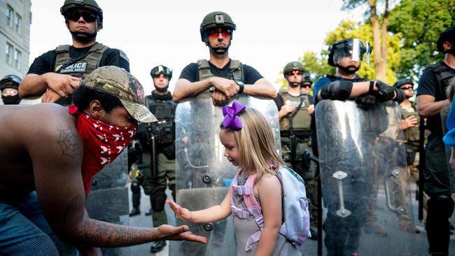 Washington DC resident, George (L), slaps hands with three-year-old Mikaela (R) in front of a police barricade on a street leading to the front of the White House during protests over the death of George Floyd.