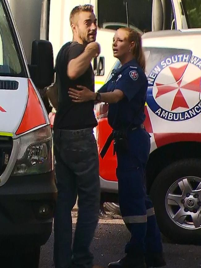 Mr Stone is comforted by a paramedic at the scene on Tuesday. Picture: TNV