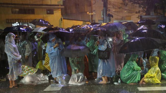 Thai people wearing raincoats and holding umbrellas queue up to take part in the Royal Cremation ceremony in Bangkok, Thailand. Picture: AP Photo/Sakchai Lalit
