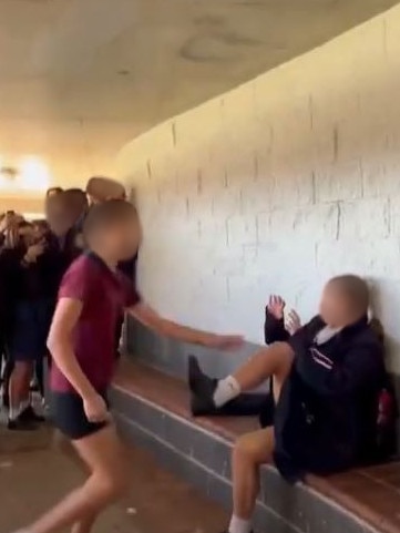 Two girls fight in the playground at Brisbane State High School as other students disgracefully cheer and film on their phones.