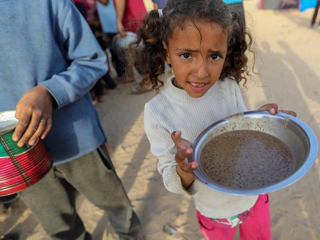 A girl lines up to receive food cooked in large pots and distributed for free before breaking the fast during Ramadan in Rafah, Gaza. Picture: Getty Images