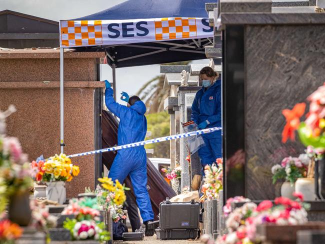 Police examine the area after human remains were stolen from Footscray cemetery. Picture: Jason Edwards