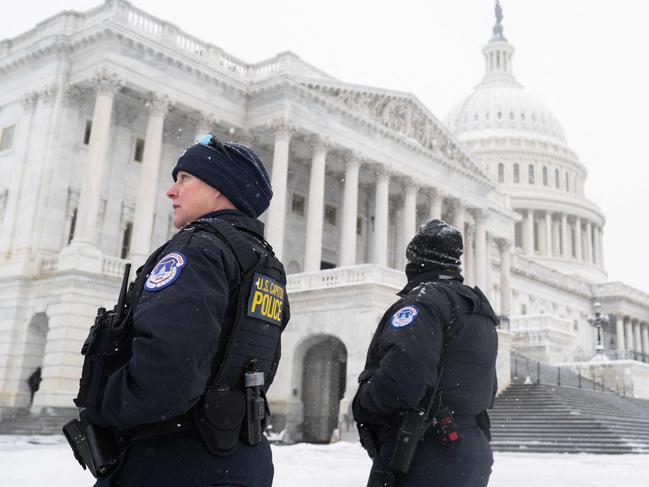 Police officers stand watch outside the US Capitol building as snow falls ahead of the joint session of the US Congress. Picture: SAUL LOEB / AFP