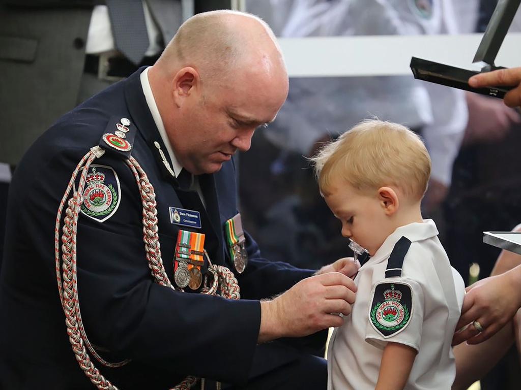 NSW RFS commissioner Shane Fitzsimmons pins a medal on Harvey Keaton after his father Geoffrey Keaton was posthumously honoured. Picture: AFP