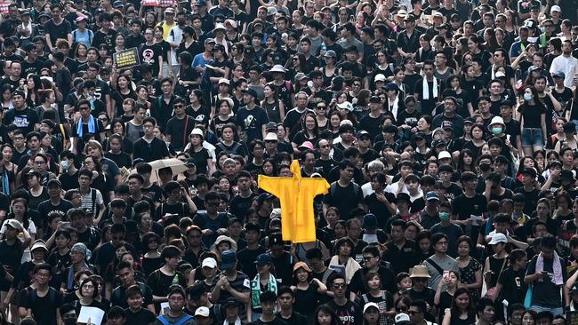 TOPSHOT - Protesters hold up a yellow raincoat in memory of a fellow protester who fell to his death the night before as they march at new rally against a controversial extradition law proposal in Hong Kong on June 16, 2019. - Tens of thousands of people rallied in central Hong Kong on June 16 as public anger seethed following unprecedented clashes between protesters and police over an extradition law, despite a climbdown by the city's embattled leader. (Photo by Anthony WALLACE / AFP)