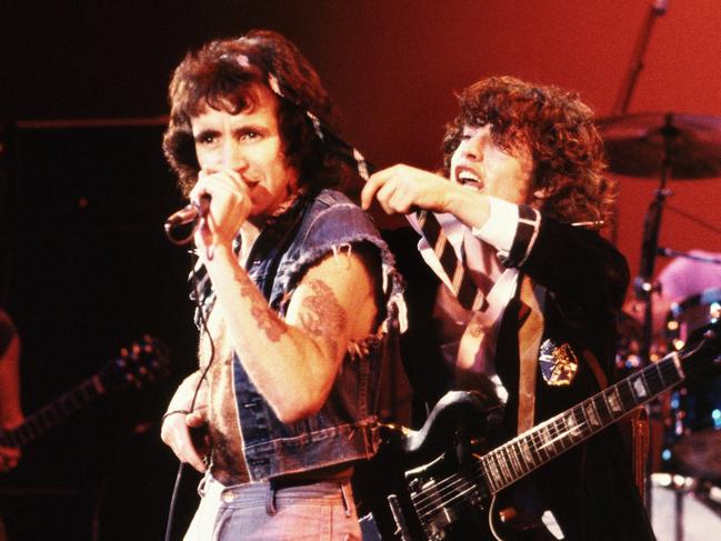 HOLLYWOOD - CIRCA 1977:  Singer Bon Scott and guitarist Angus Young of AC/DC put on a show for the crowd circa 1977 in Hollywood, California. In the background can be seen rhythm guitarist Malcolm Young and drummer Phil Rudd. (Photo by Michael Ochs Archives/Getty Images)