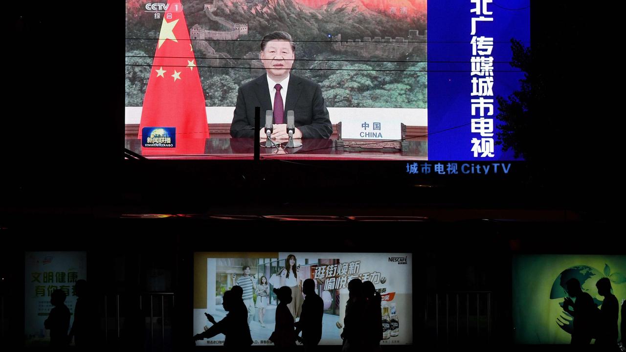 Chinese President Xi Jinping appearing by video link at the United Nations 75th anniversary is seen on an outdoor screen as pedestrians walk past below in Beijing. Picture: Greg Baker/AFP