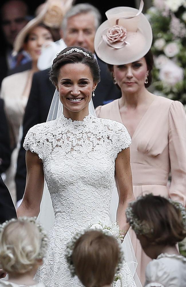 Pippa Middleton beams as she leaves the church with sister Kate behind her.