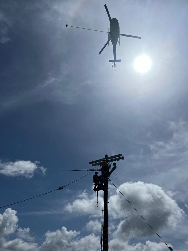 Helicopters were used to plant taller and heavier power poles along a rebuilt power network after record flooding following Cyclone Jasper washed away Ergon's pre-existing network. Photo: Supplied.