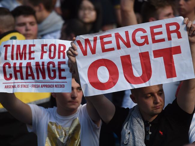 (FILES) This file photo taken on May 08, 2016 shows Arsenal fans holding up signs calling for the resignation of Arsenal's French manager Arsene Wenger after the English Premier League football match between Manchester City and Arsenal at the Etihad Stadium in Manchester, north west England, on May 8, 2016. Arsene Wenger memorably announced his arrival as a revolutionary force in England by banning his players from eating sweets, but the Arsenal manager's reign has turned increasingly sour as he marks the 20th anniversary of his appointment. Forced to endure verbal abuse and calls for his resignation, Wenger has been battered like never before over the past 18 months. And failure again this season to win either the Premier League or Champions League could spell the end of one of English football's most celebrated figures -- and with it the closing of an era. / AFP PHOTO / PAUL ELLIS / RESTRICTED TO EDITORIAL USE. No use with unauthorized audio, video, data, fixture lists, club/league logos or 'live' services. Online in-match use limited to 75 images, no video emulation. No use in betting, games or single club/league/player publications. / TO GO WITH STORY BY STEVEN GRIFFITHS