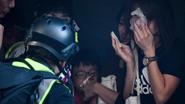 A child and other bystanders receive treatment by a medic volunteer, left, after police fired teargas to disperse protesters in Kowloon, in Hong Kong. Picture: AFP