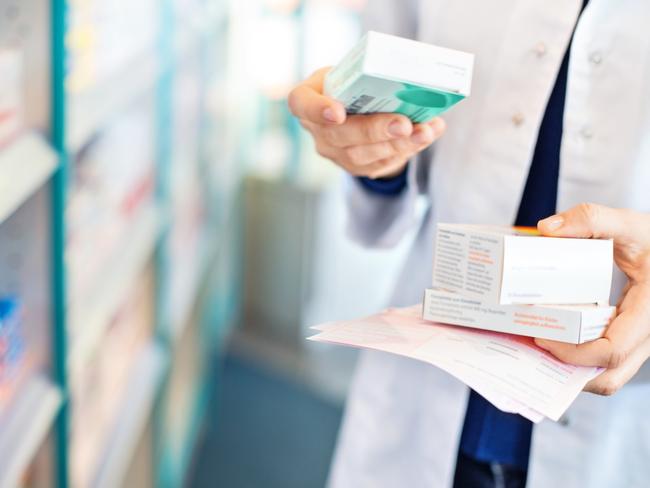 Closeup of pharmacist's hands taking medicines from shelf at the pharmacy