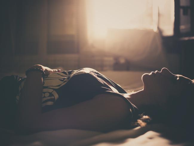 Sad girl in bed, backlit scene. Desaturated image.